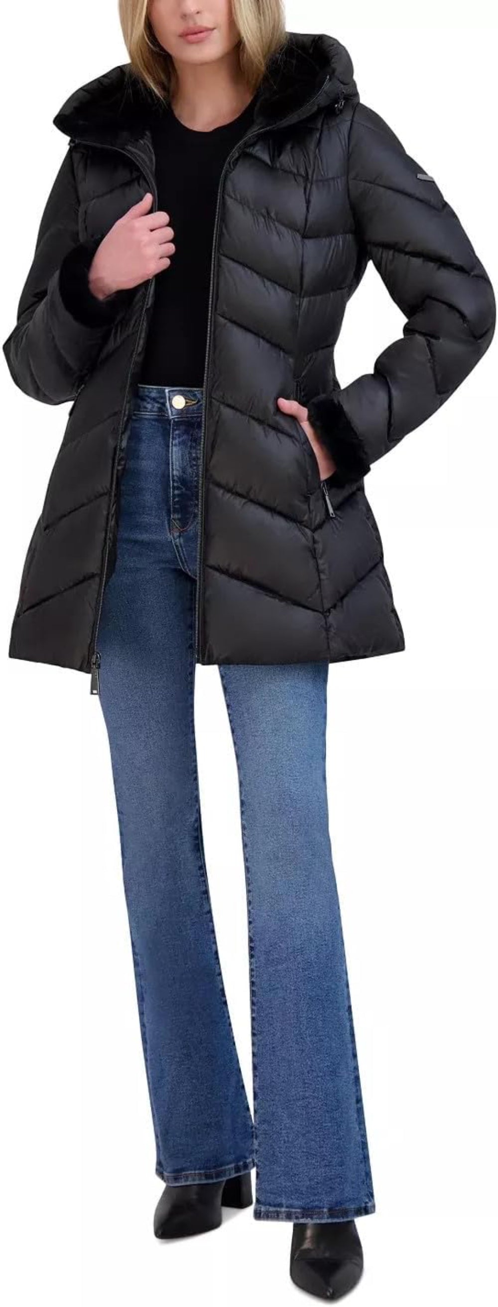 Person wearing a black puffer coat and blue jeans on a white background