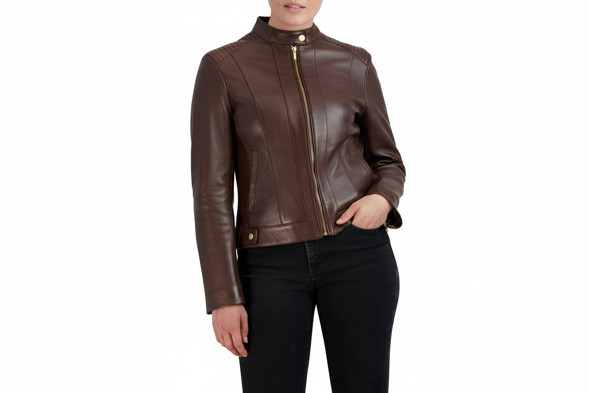 A woman wearing a chocolate leather moto jacket with gold-tone hardware, paired with black jeans, shown against a plain white background.