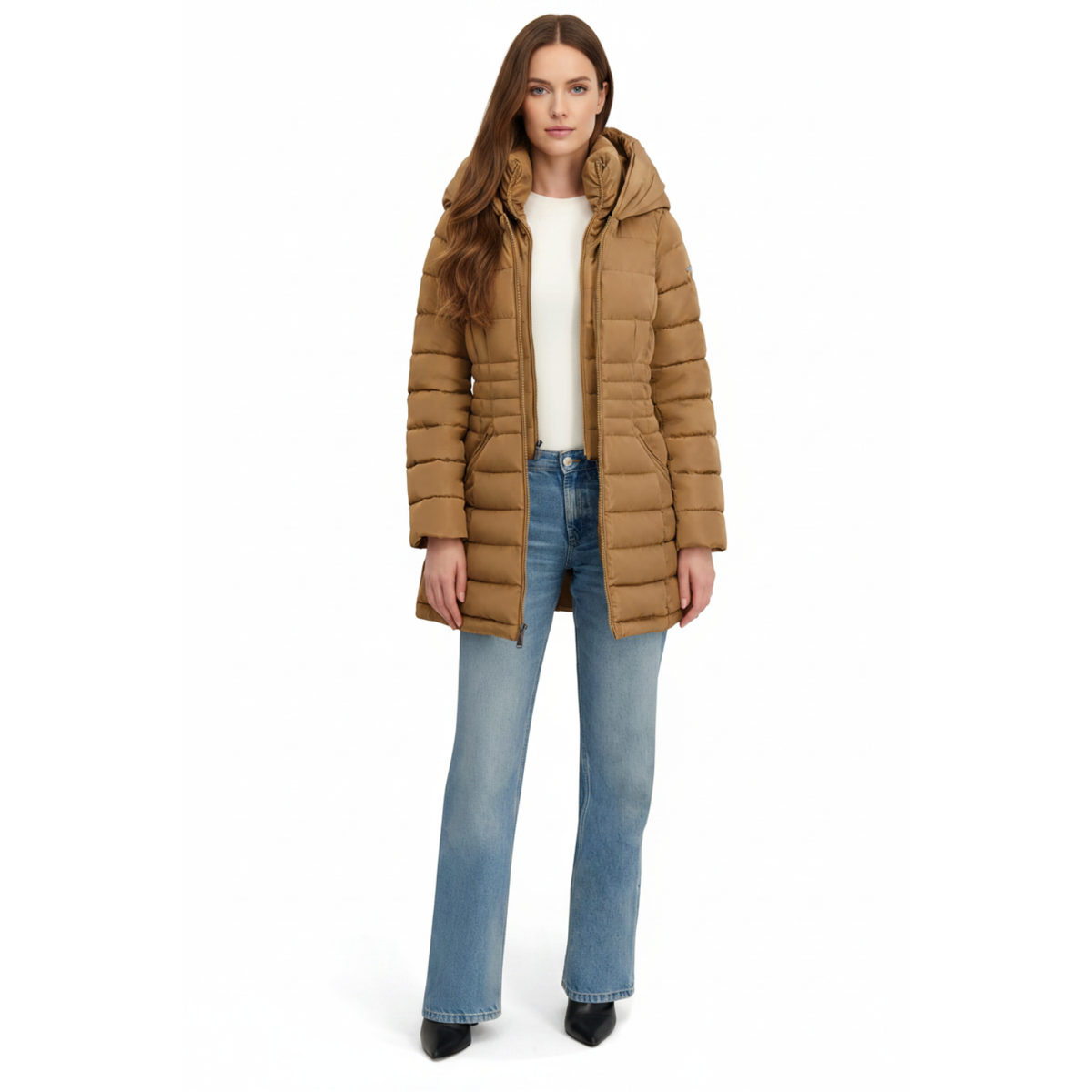 A woman modeling a tan hooded puffer jacket over a white top and blue jeans, photographed against a plain white studio background.