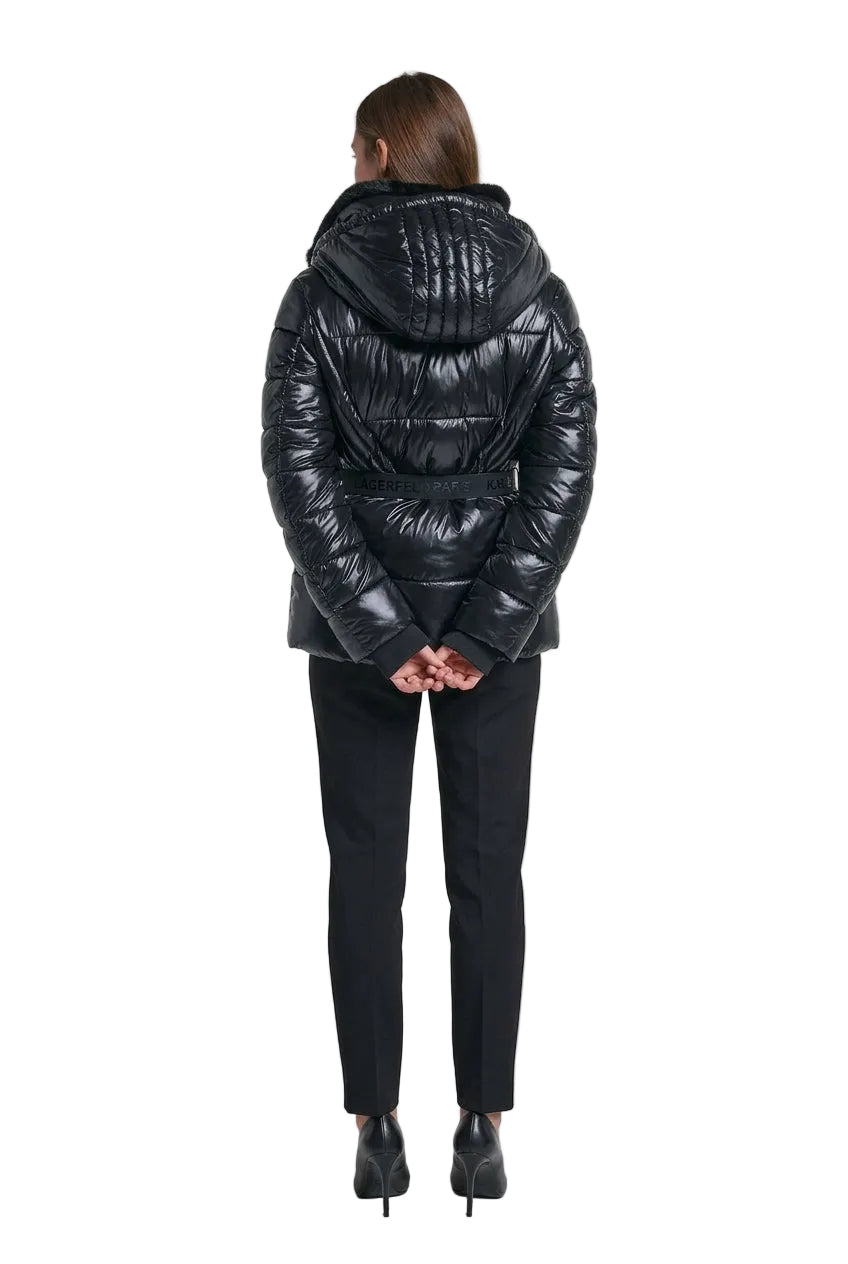 A woman shown from the back wearing a shiny black puffer jacket with a fur-trimmed hood and a matching black belt