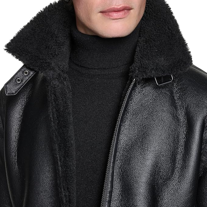 Close-up of a person wearing a black textured leather jacket with a thick black shearling-style collar over a black turtleneck sweater, against a plain white background.